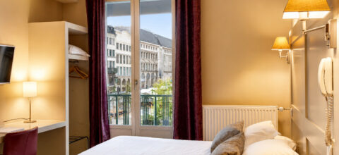 Chambre lumineuse de l’Hôtel Cardinal Rouen avec balcon face à la cathédrale Notre-Dame